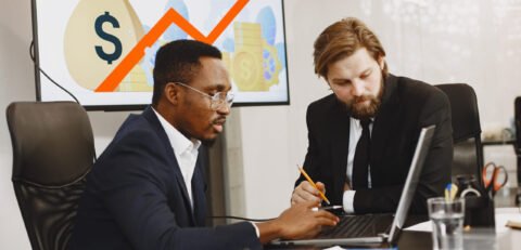 African man in a black suit. International partners. People sitting at the table with laptop.