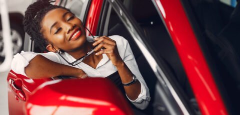 Woman buying the car. Lady in a car salon. Elegant black girl