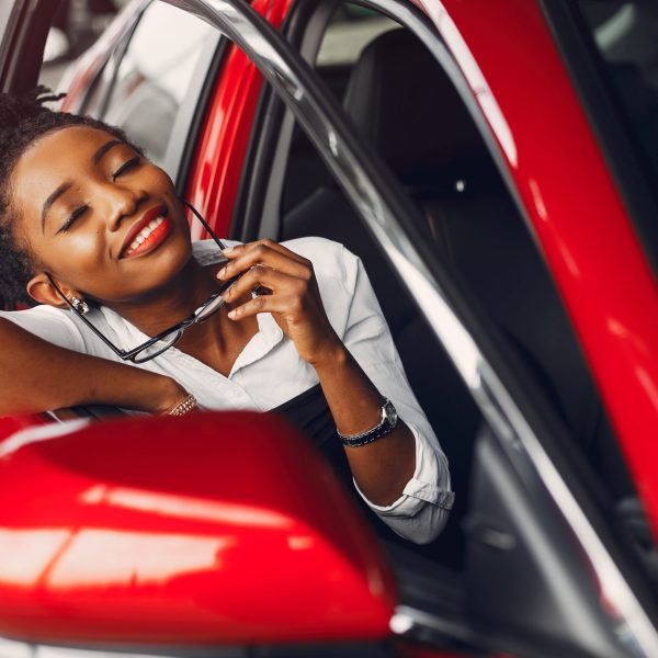 Woman buying the car. Lady in a car salon. Elegant black girl